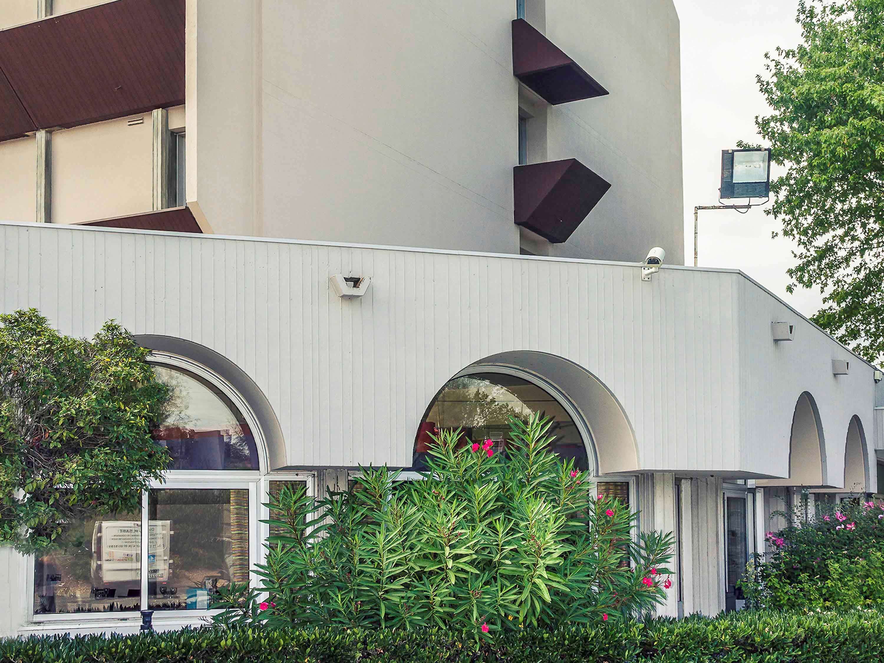 Un edificio moderno con amplias ventanas arqueadas y fachada blanca.