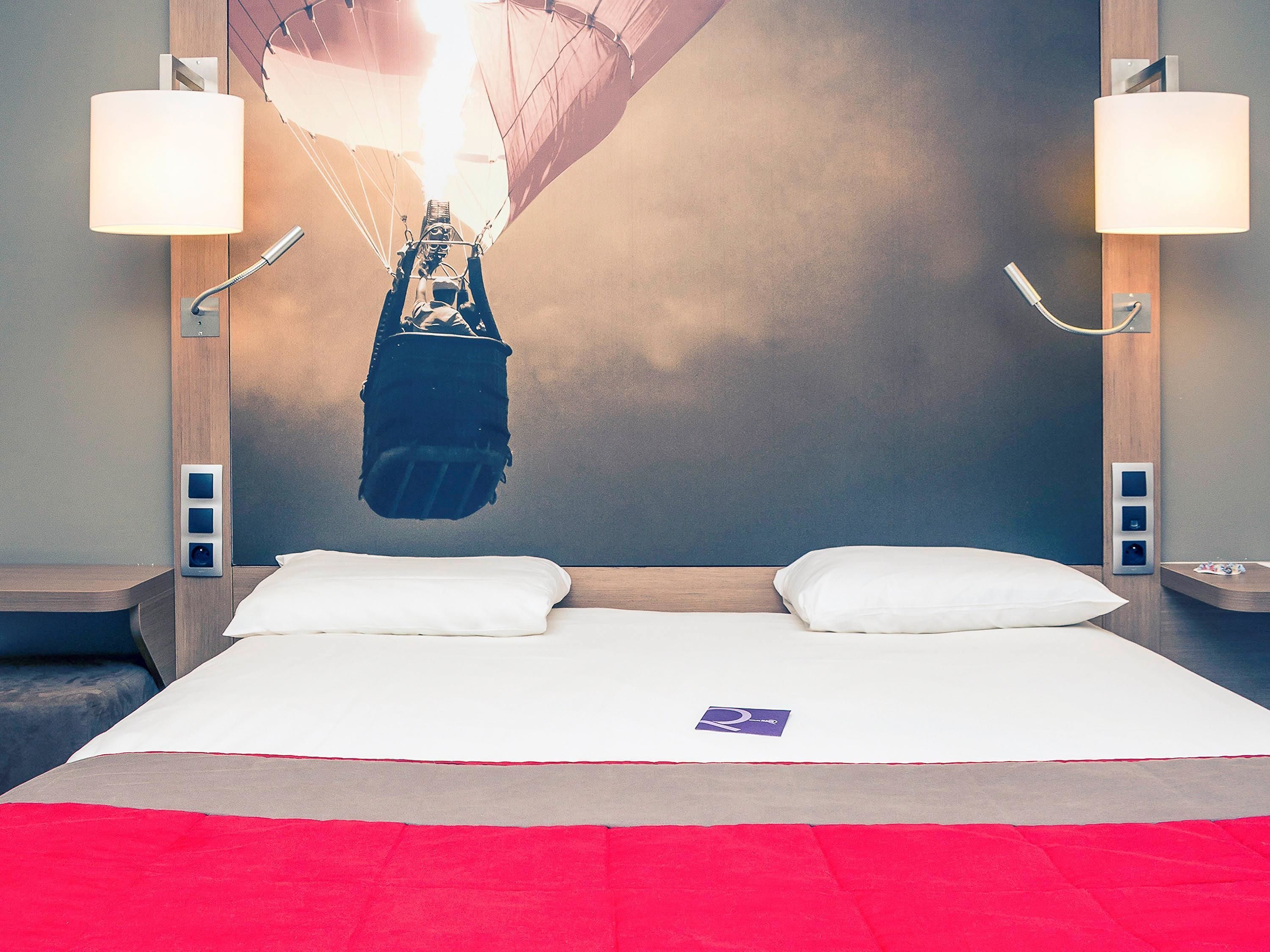 Ein Hotelzimmer mit einem großen Bett, zwei Nachttischlampen und einem einzigartigen Hängekorbsessel, der von der Decke hängt.