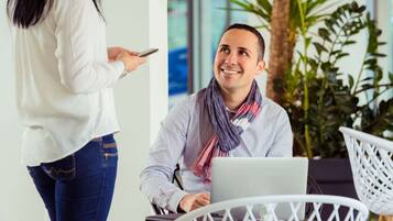 A person using a laptop in a modern office setting with white furniture and indoor plants.