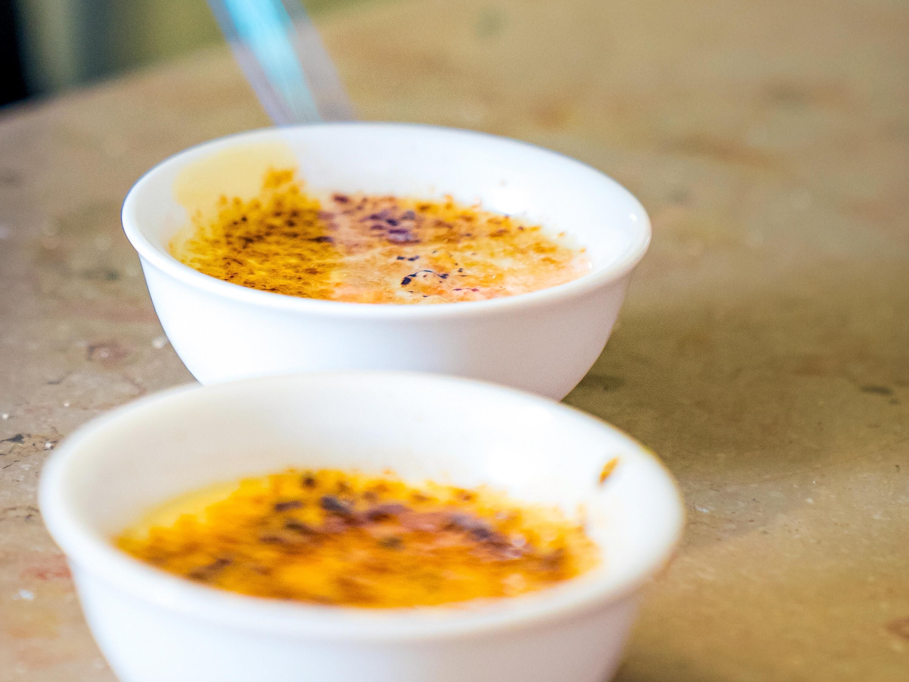 Two white bowls with a creamy dessert on a textured surface.
