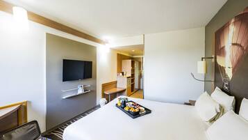 Hotelkamer met een bed, een flatscreen-tv, een bureau en een dienblad met ontbijtartikelen.