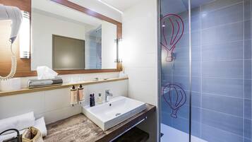 A modern bathroom with a large mirror, a sink, a towel rack, and a glass shower enclosure.