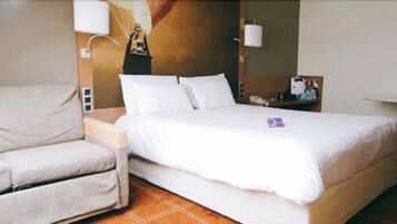 Una habitación de hotel con cama, una silla, un escritorio y un teléfono en la pared.