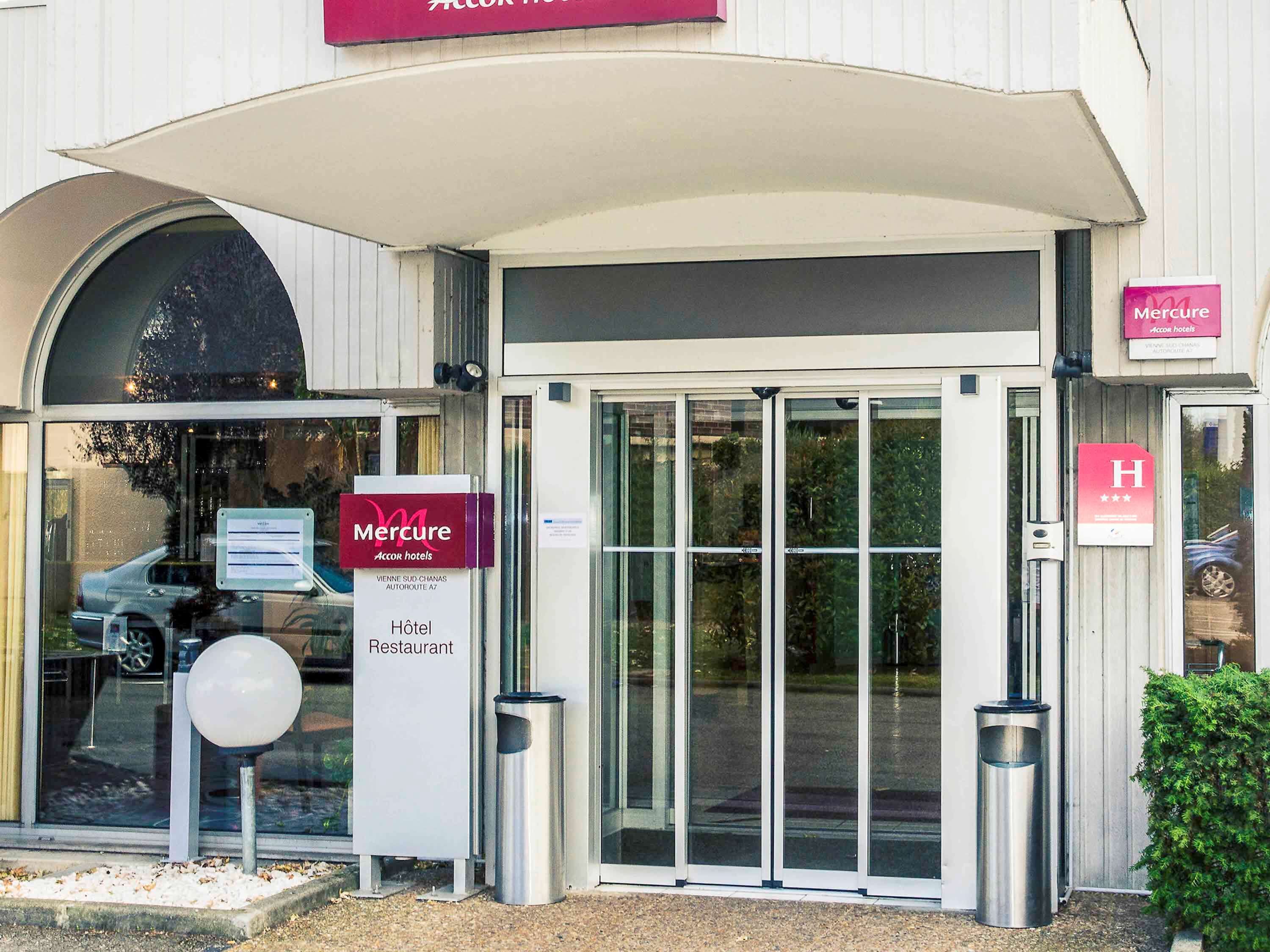 A Mercure Accor hotel entrance with a glass door, a sign indicating the hotel and restaurant, and a parking sign.