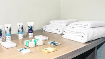 Artículos de tocador y toallas sobre una encimera de madera en un baño de hotel.