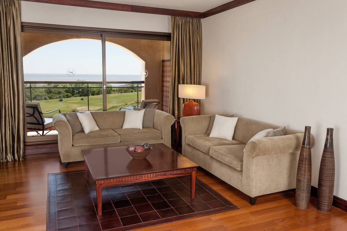 Una habitación con dos sofás, una mesita de centro y dos jarrones altos.