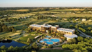 A large resort with multiple swimming pools, a golf course, and a large building with a modern architectural style.