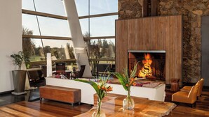 A modern interior with a stone wall, a fireplace, and a large window overlooking a landscape.
