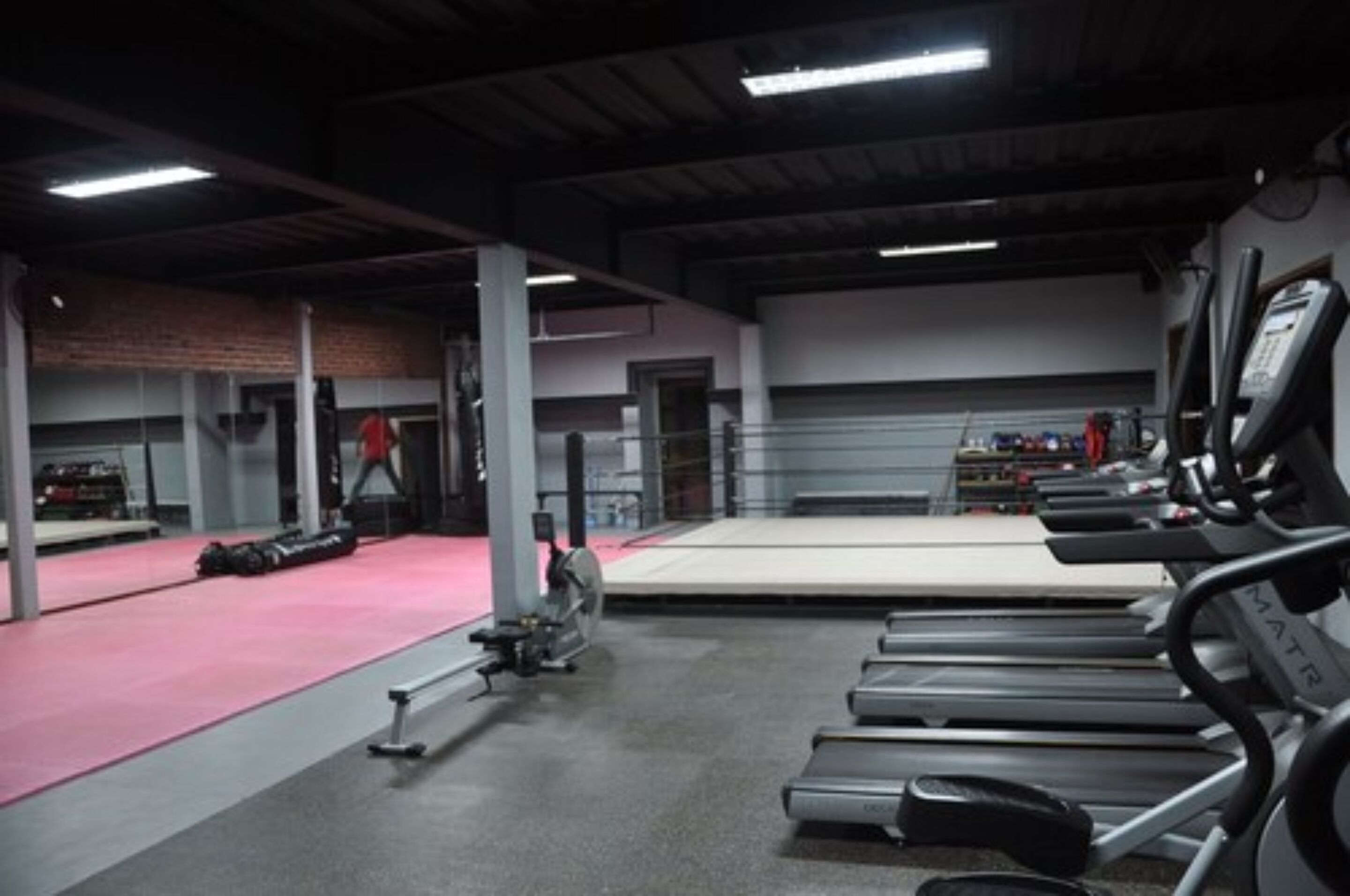 Une salle de sport équipée de tapis de course, d’une zone avec des tapis rouges et de matériel d’exercice.