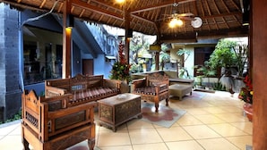 A traditional wooden lounge with thatched roof, cushioned seating, and potted plants. - Putu Bali Villa and Spa (Seminyak)