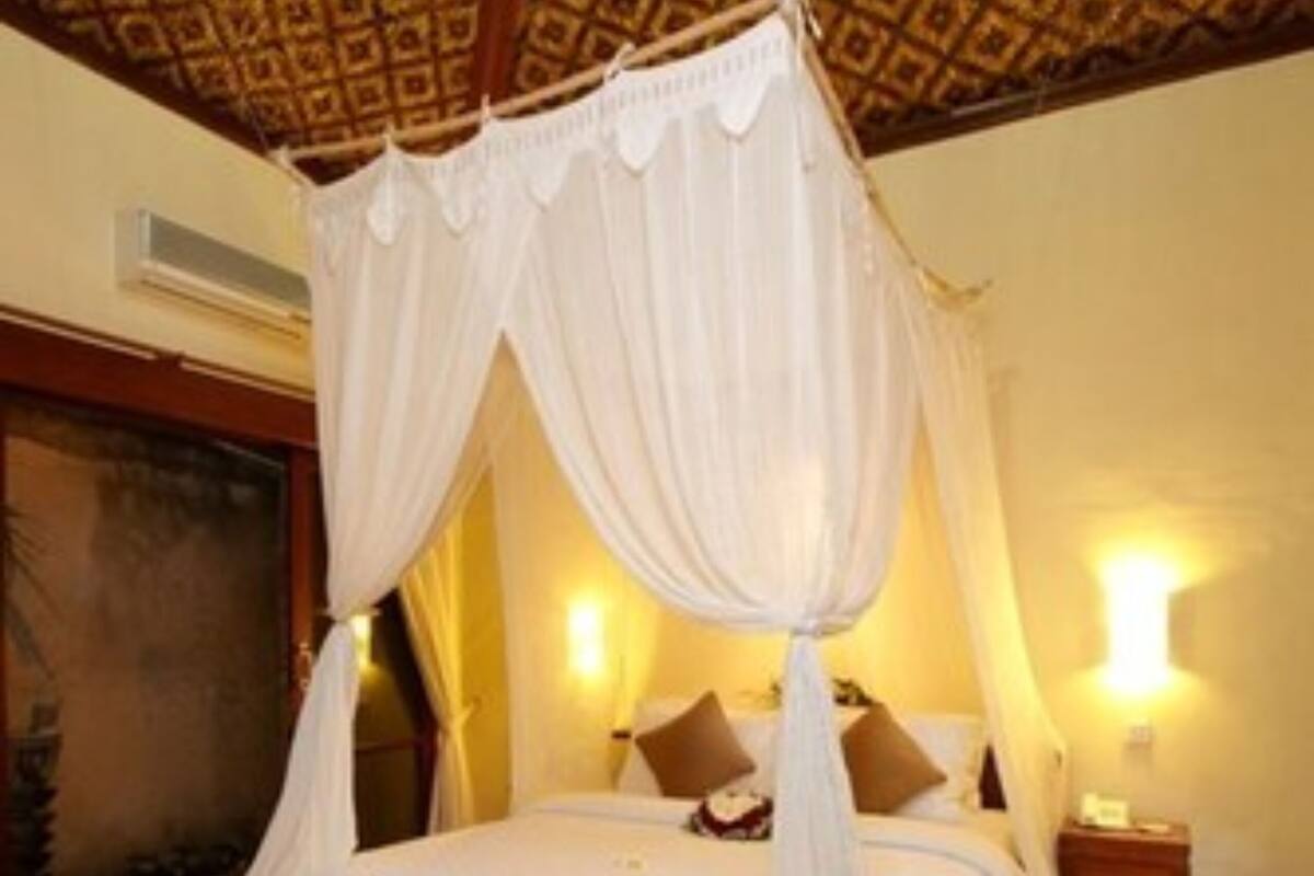 A four-poster bed with a canopy, a nightstand, and a wall-mounted lamp.
