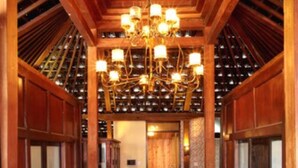 A wooden hallway with a chandelier, a potted plant, and a door at the end. - Putu Bali Villa and Spa (Seminyak)
