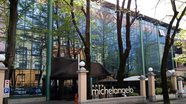 Un edificio moderno con fachada de vidrio y un letrero que dice 'Michelangelo'.