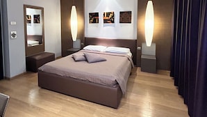 Una habitación de hotel moderna con una cama grande, mesitas de noche, un espejo y obras de arte en las paredes.