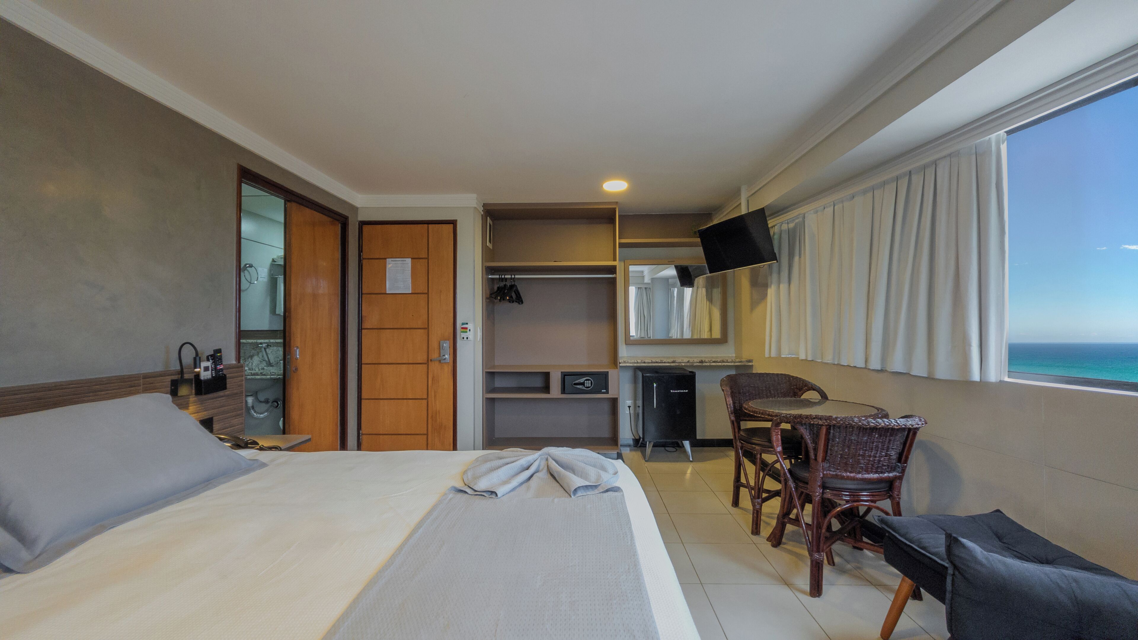 Ein Hotelzimmer mit Bett, Schreibtisch, Sessel, Fernseher und Meerblick.