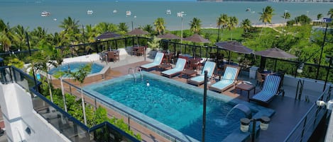 Una piscina al aire libre, sombrillas, tumbonas