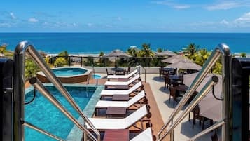 Una piscina al aire libre, sombrillas, sillones reclinables de piscina