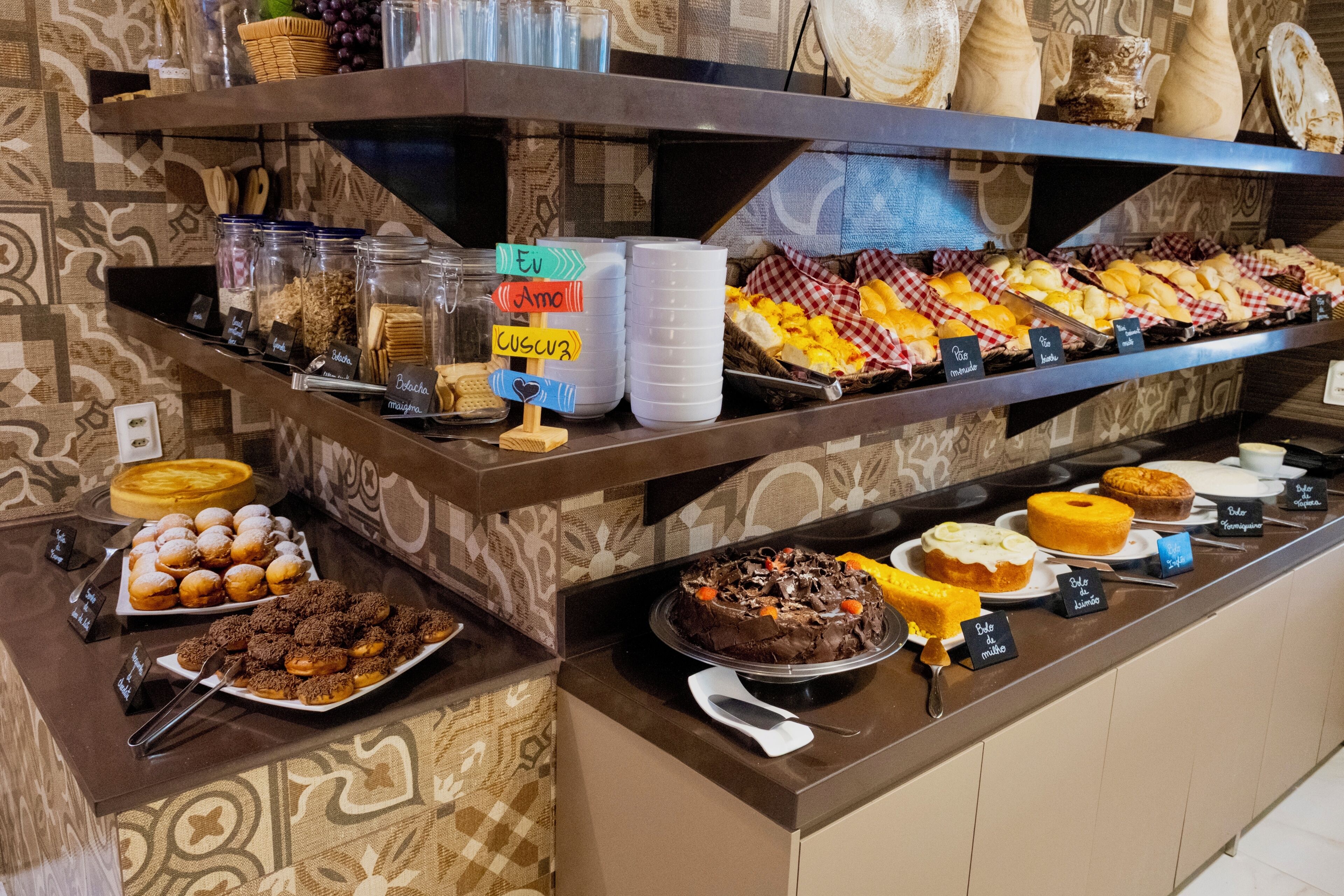 Buffet com diversos alimentos e um aviso indicando a direção ao banheiro.