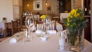 A dining table set with wine glasses, a vase with yellow flowers, and a neatly folded napkin. - Finca Son Palou (Bunyola)