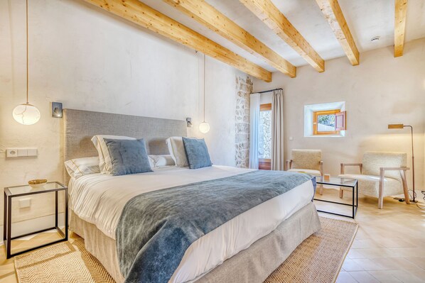 Une chambre à coucher avec un lit, des tables de chevet, une chaise, une fenêtre et un tableau au mur.