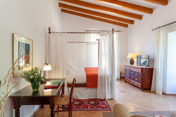 Une chambre à coucher avec un lit, une table de chevet avec une lampe, une commode, une chaise et une fenêtre avec des rideaux.