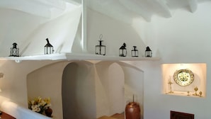 A cozy interior with a white fireplace, a shelf with lanterns, and a tiled floor. - Finca Son Palou (Bunyola)