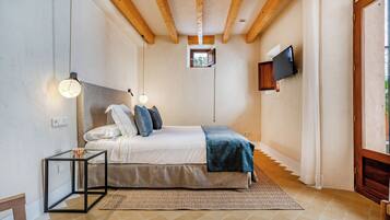 Un dormitorio con cama, mesitas de noche, televisor y ventana.