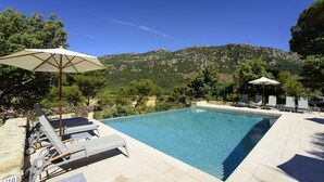 A swimming pool with lounge chairs and umbrellas, surrounded by greenery and mountains. - Finca Son Palou (Bunyola)