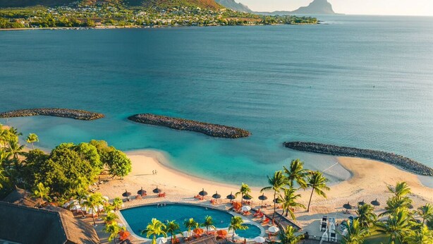 Un complexe hôtelier doté d’une piscine, d’une plage et offrant une vue sur les montagnes.