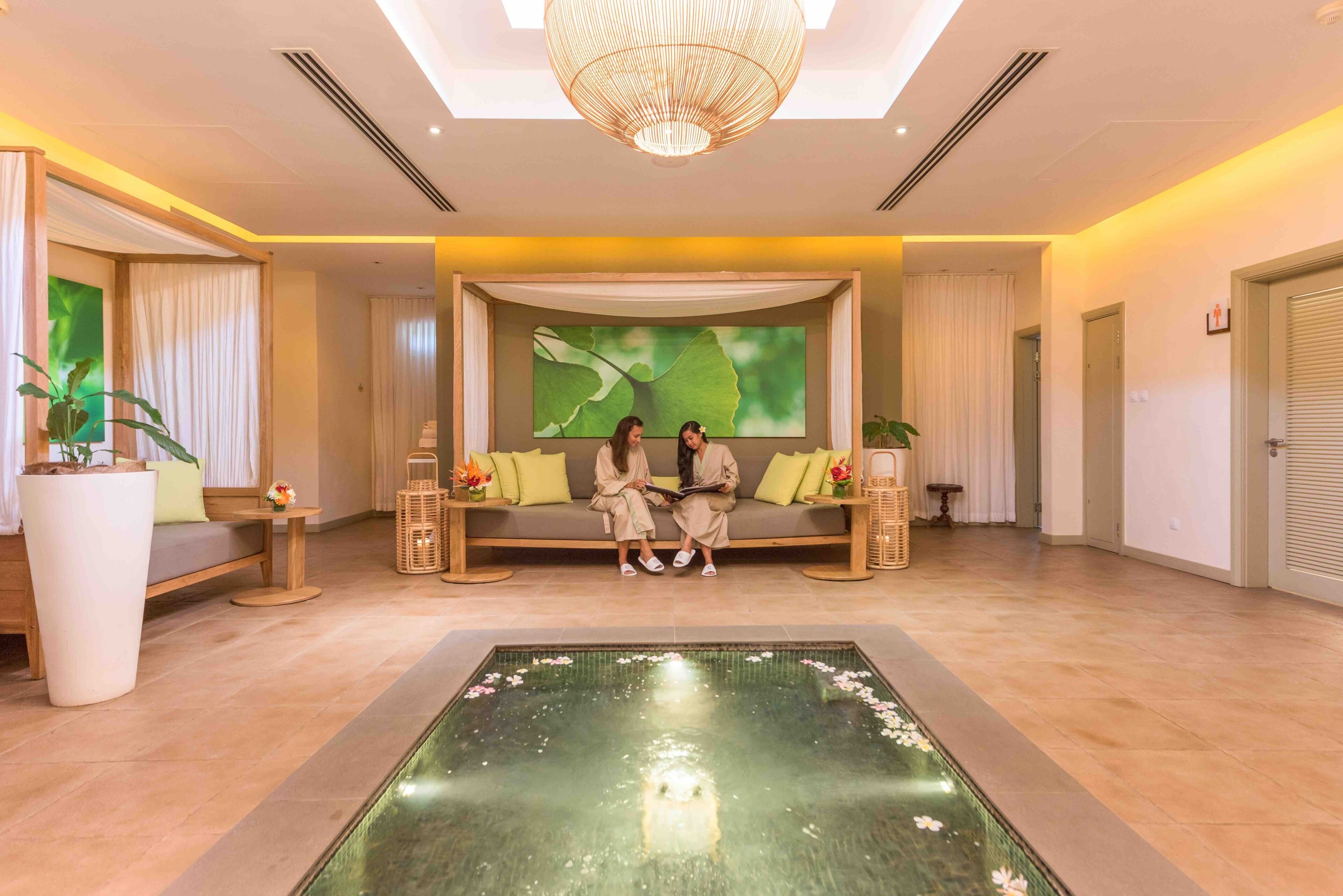A spacious lobby with a central seating area, a large water feature, and a modern chandelier.
