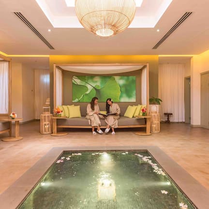 A spacious lobby with a central seating area, a large water feature, and a modern chandelier.