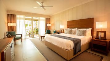 Una habitación de hotel con una cama grande, un escritorio, una silla y un ventilador de techo.