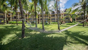 Un resort con edificios de varios pisos, palmeras y una hamaca en el patio.