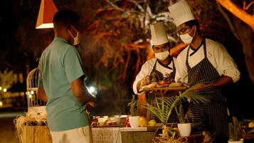 Un chef préparant et servant des plats en plein air, la nuit.