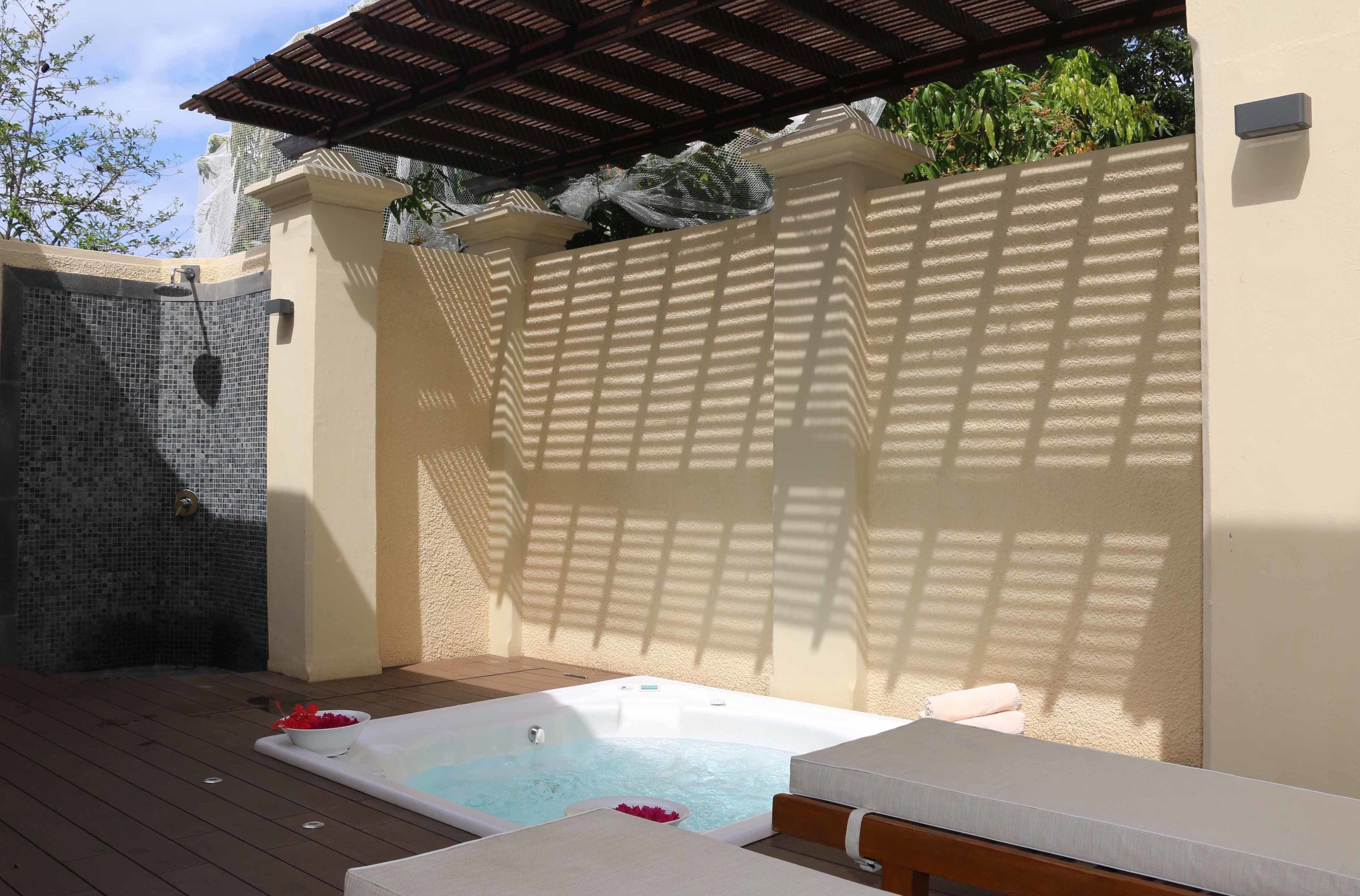 Un espace bien-être comprenant un jacuzzi, une terrasse en bois et un coin salon abrité.