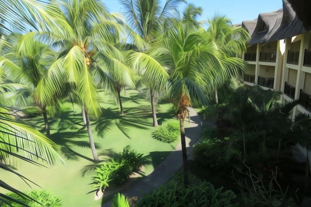 Ein Resort mit Palmen, einem Pool und einem Gebäude mit Balkonen.