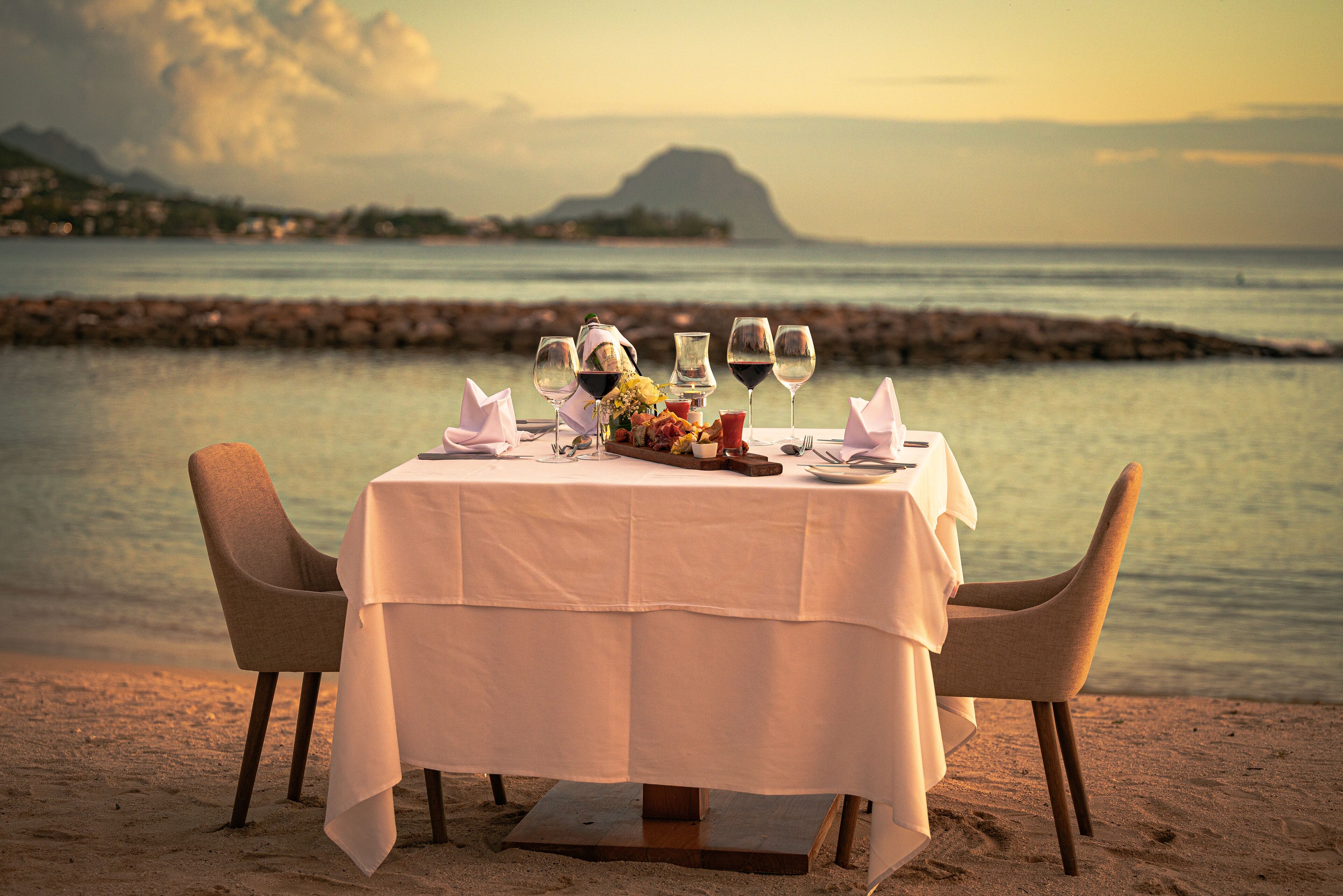 A table set for two with a view of the sea and mountains in the background.