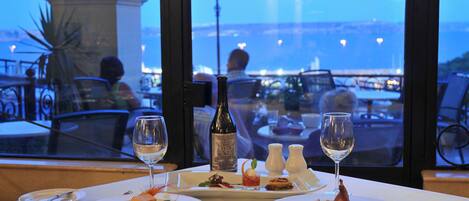 A table set for dinner with plates of food, wine glasses, and a bottle of wine.