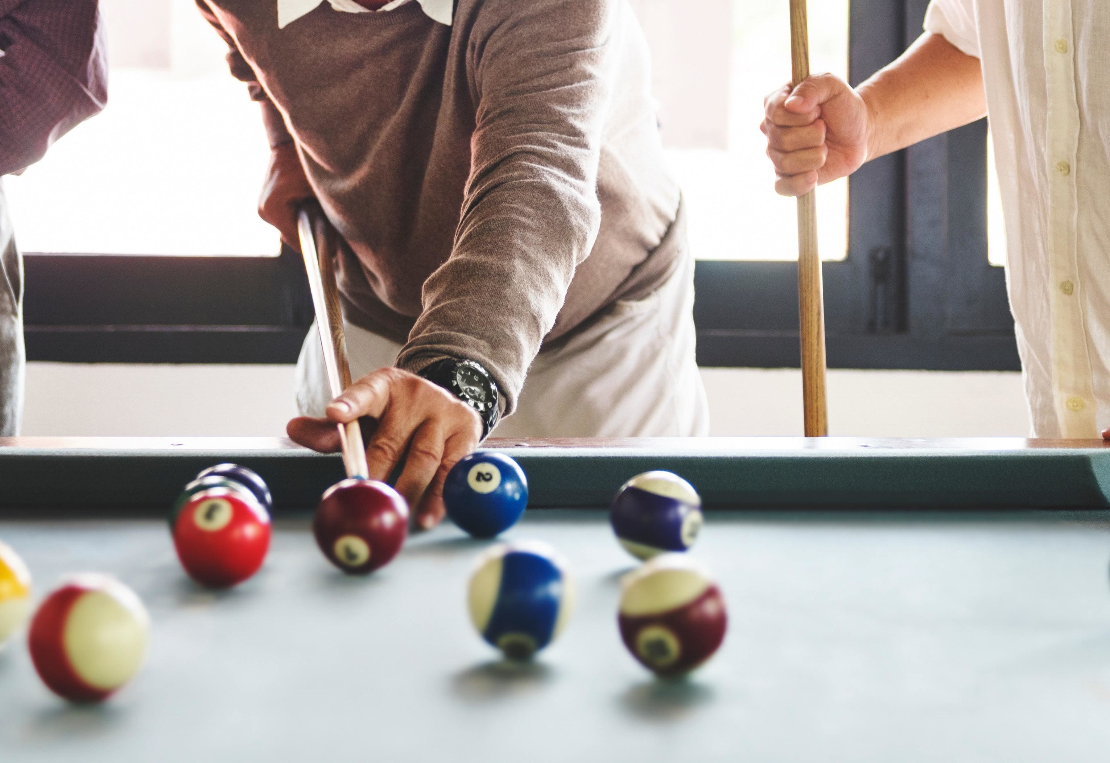 A pool table with balls and a person playing.