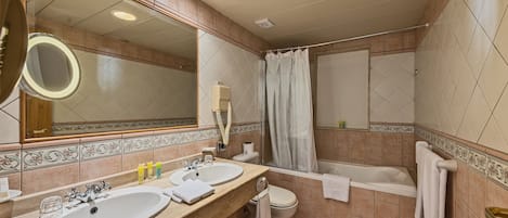 A bathroom with two sinks, a toilet, a bathtub, and a shower curtain.