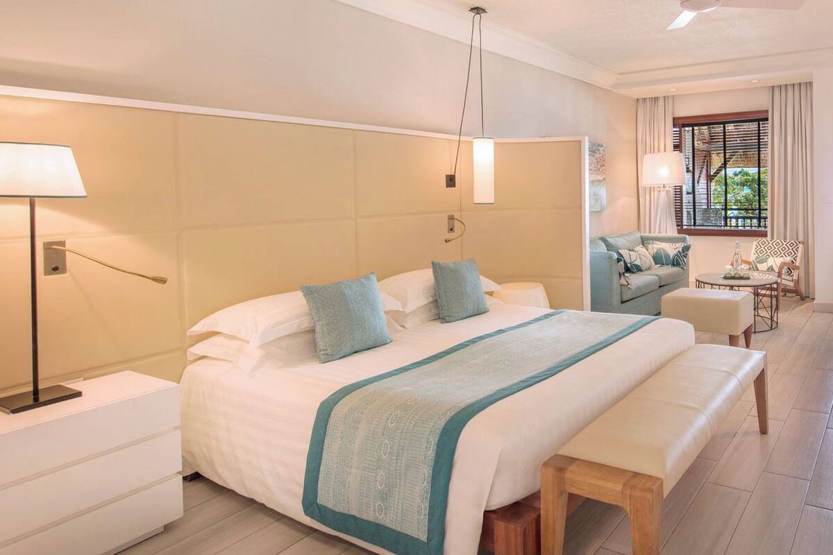 Una habitación de hotel con una cama grande, mesitas de noche, un escritorio y una silla.