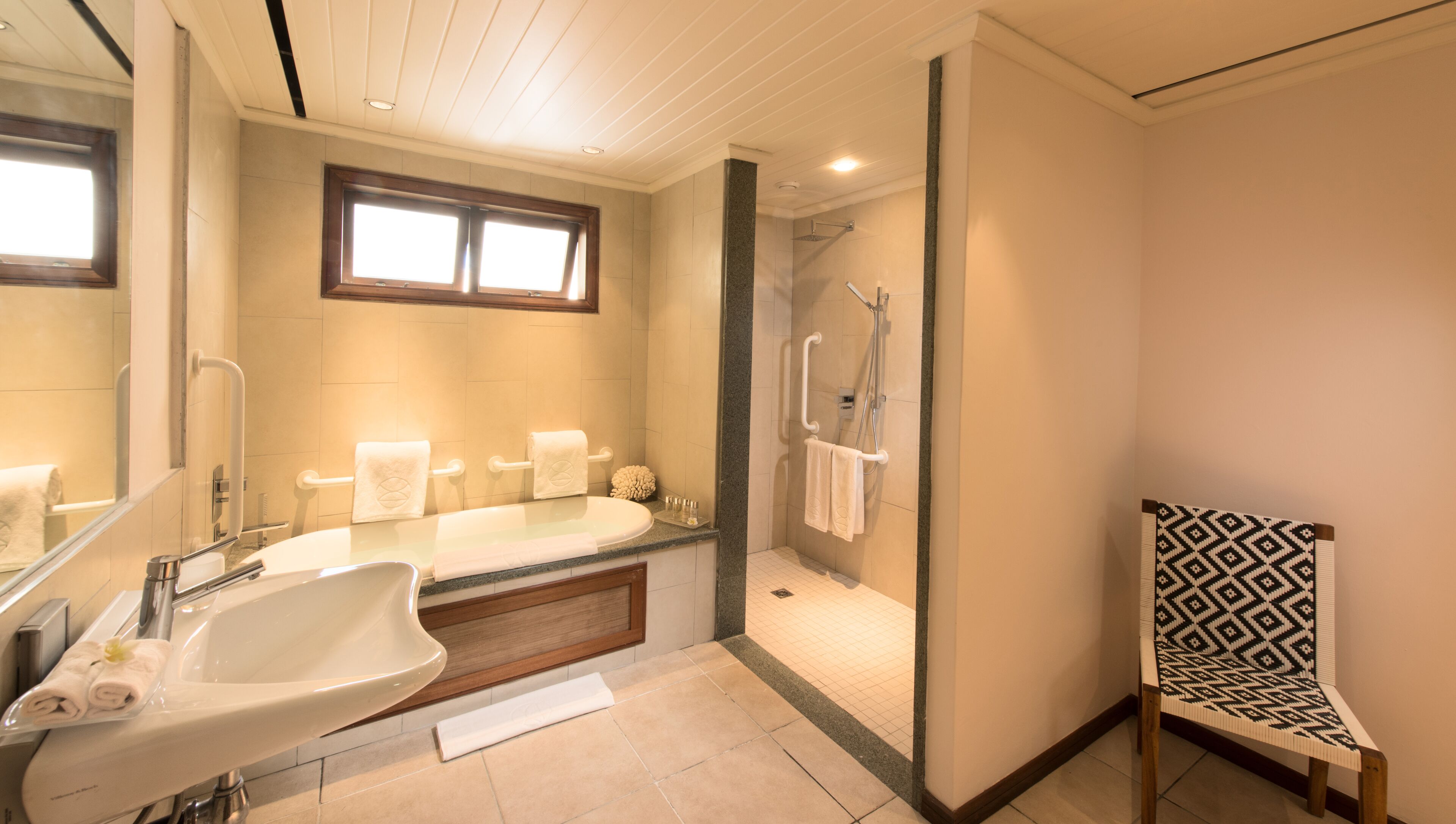 A modern bathroom with a large sink, a bathtub, a shower, and a glass-enclosed shower area.