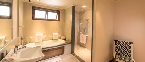 A modern bathroom with a large sink, a bathtub, a shower, and a glass-enclosed shower area.