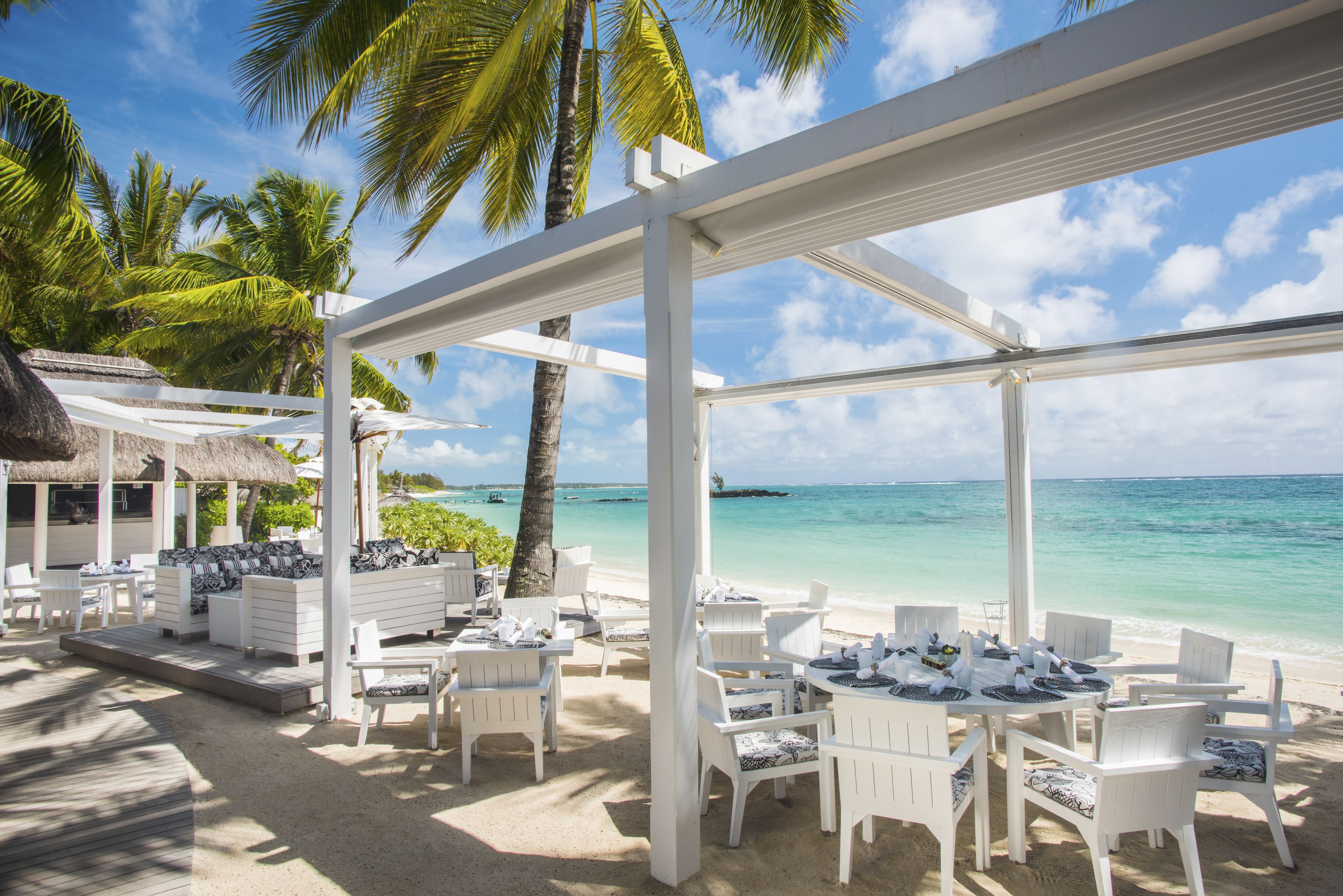 A beachside outdoor seating area with white furniture and a view of the ocean.