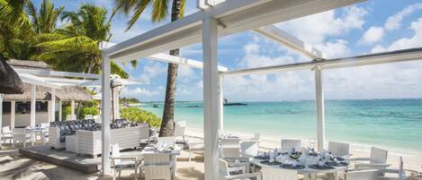 Un espace extérieur aménagé avec des meubles blancs, situé au bord de la plage et offrant une vue sur l’océan.