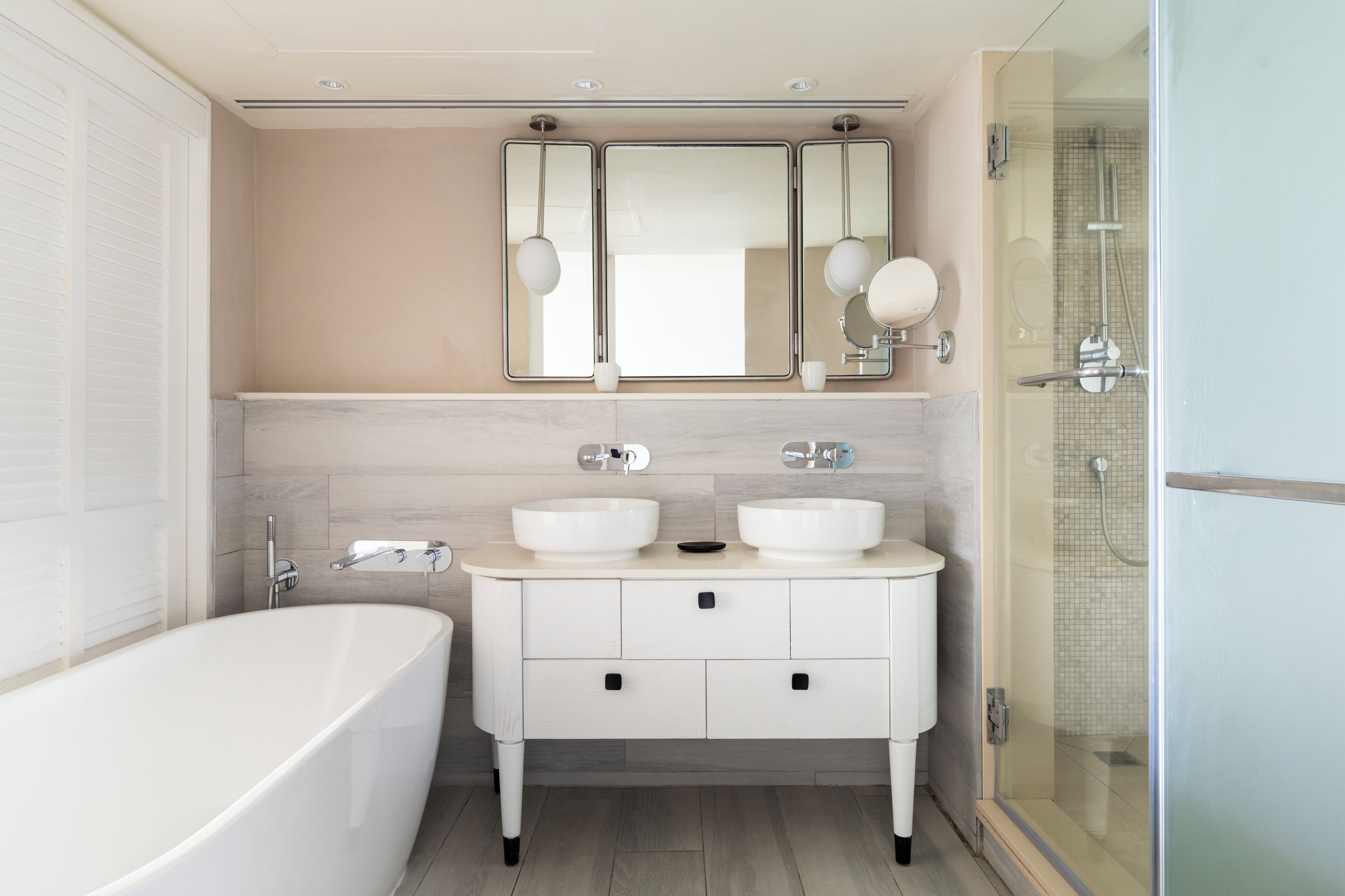 A modern bathroom with a freestanding bathtub, a vanity with two sinks, and a glass-enclosed shower.