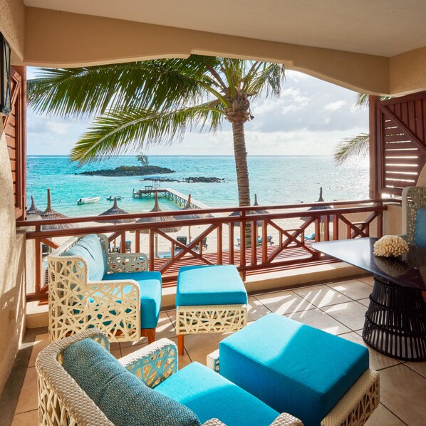 A balcony with wicker furniture and a view of the ocean.