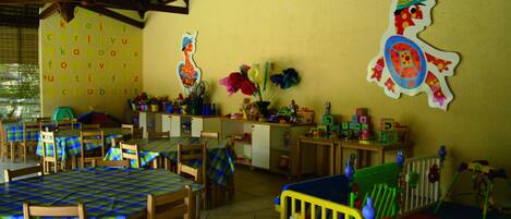 A room with a high ceiling, wooden furniture, and colorful decorations including a wall with a letter chart and a turtle illustration.