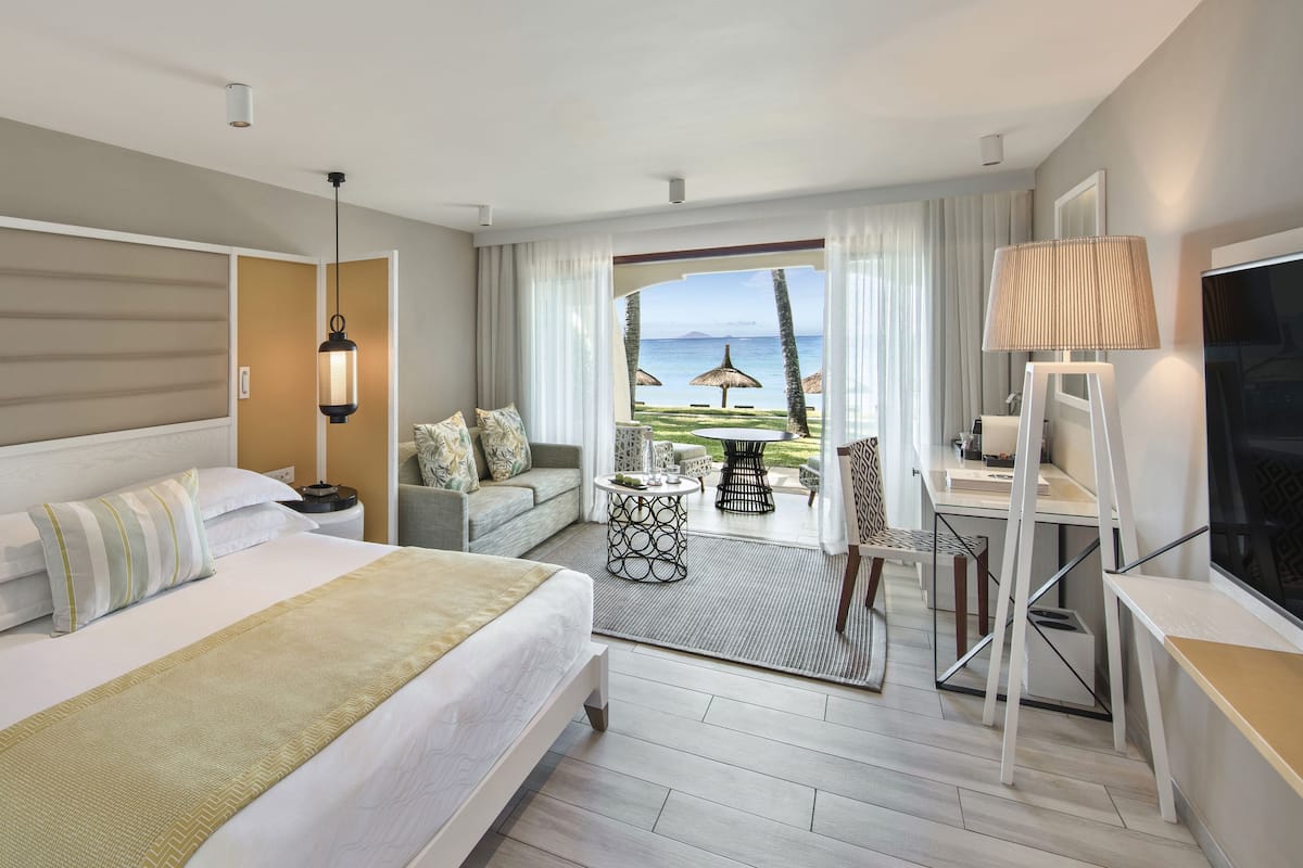 Habitación de hotel con cama, escritorio, televisión y balcón con vista a la playa.