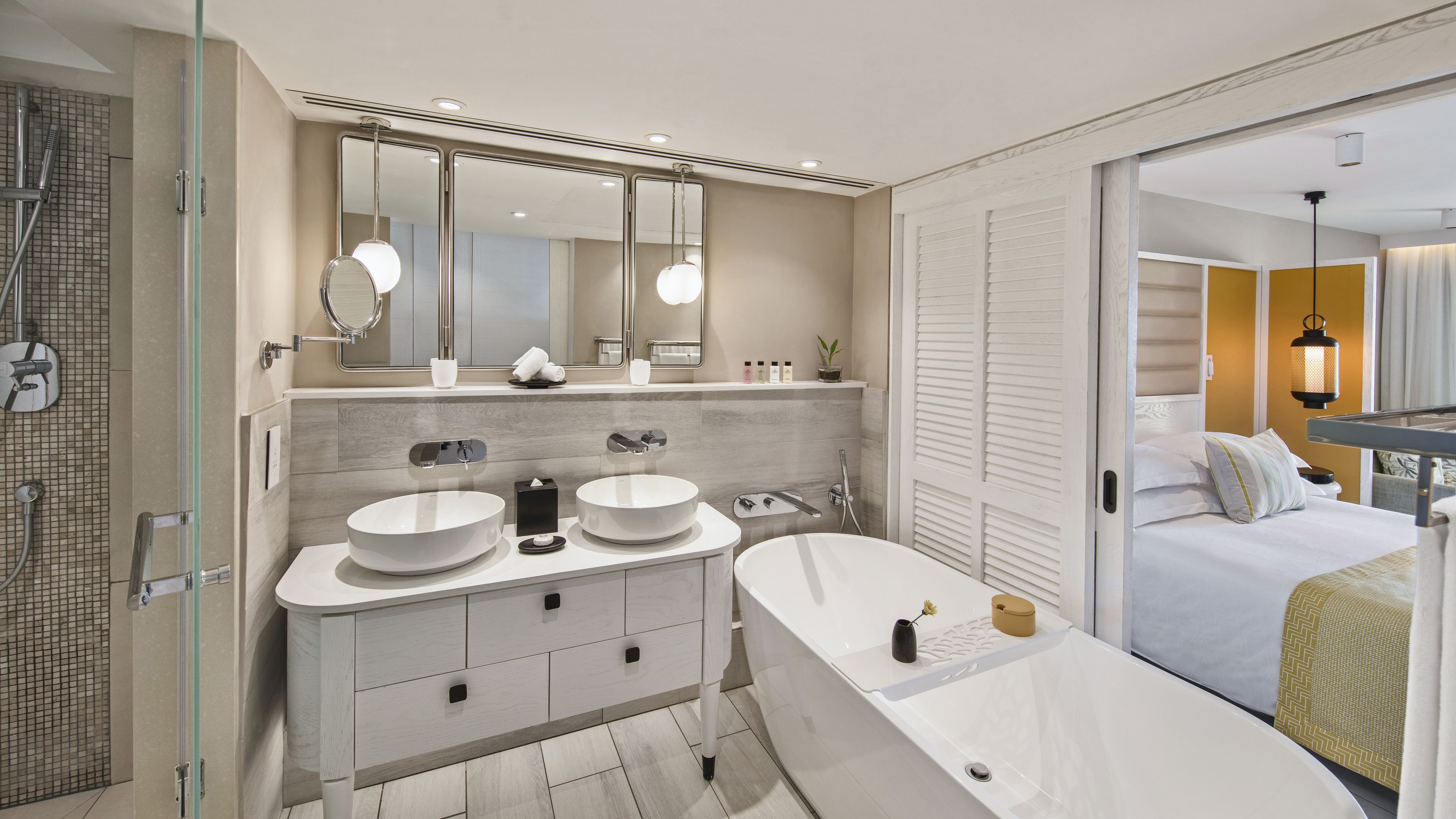 Un baño moderno con una bañera grande, dos lavamanos, una ducha a ras de suelo y un espejo amplio.
